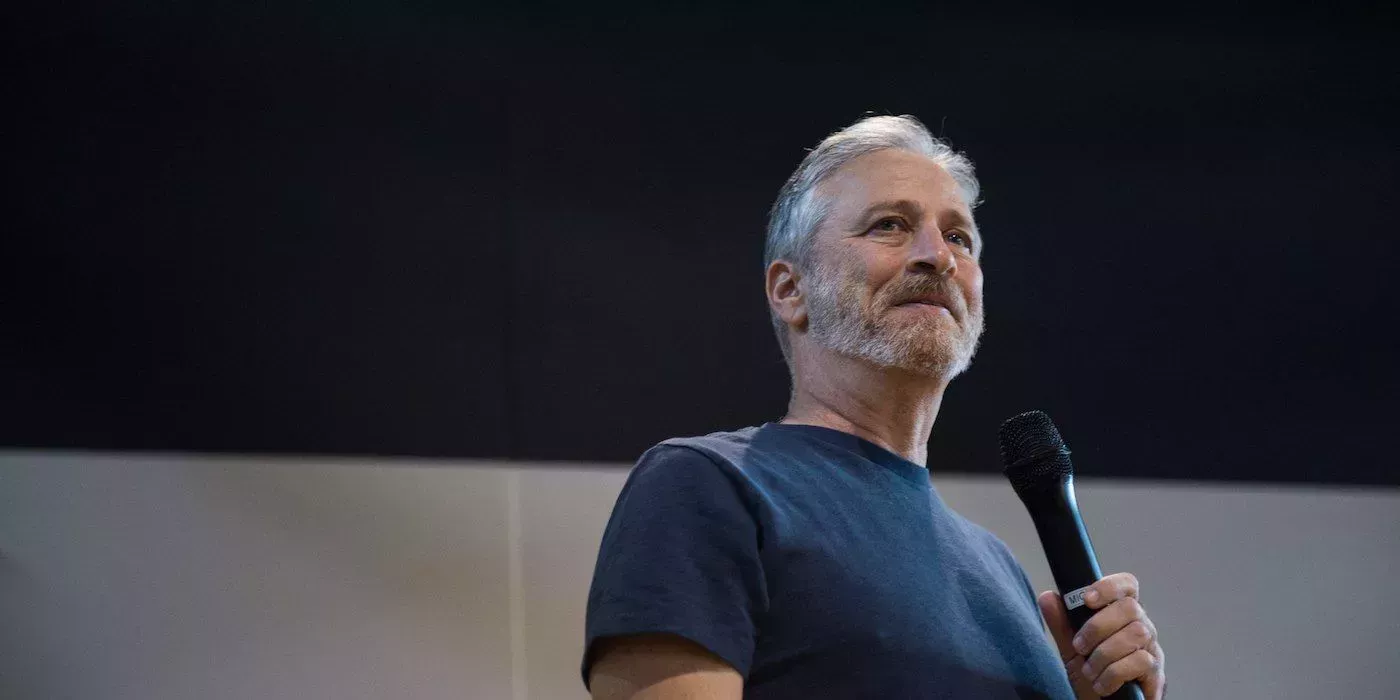 Image of Jon Stewart smiling and holding microphone