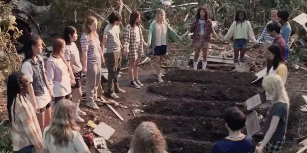 The Yellowjackets cast holding hands in a circle as they bury their teammates