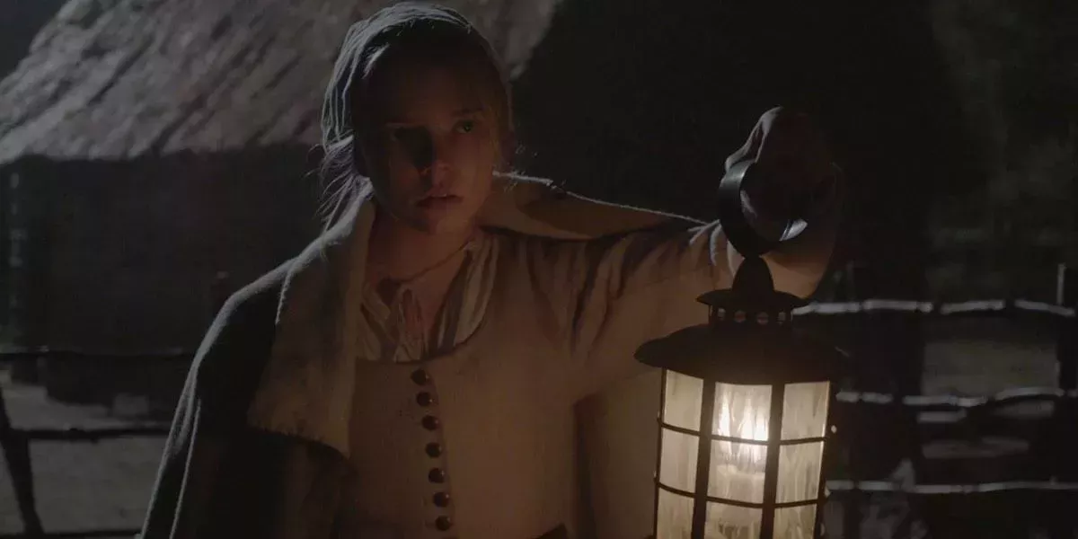 Thomasin explores the night with a lamp in The Witch
