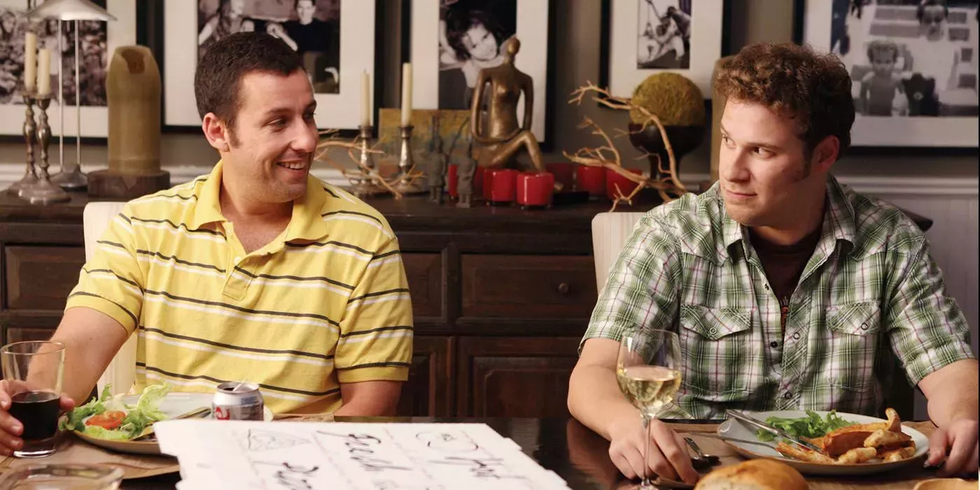 Adam Sandler sitting next to Seth Rogen and smiling in Funny People