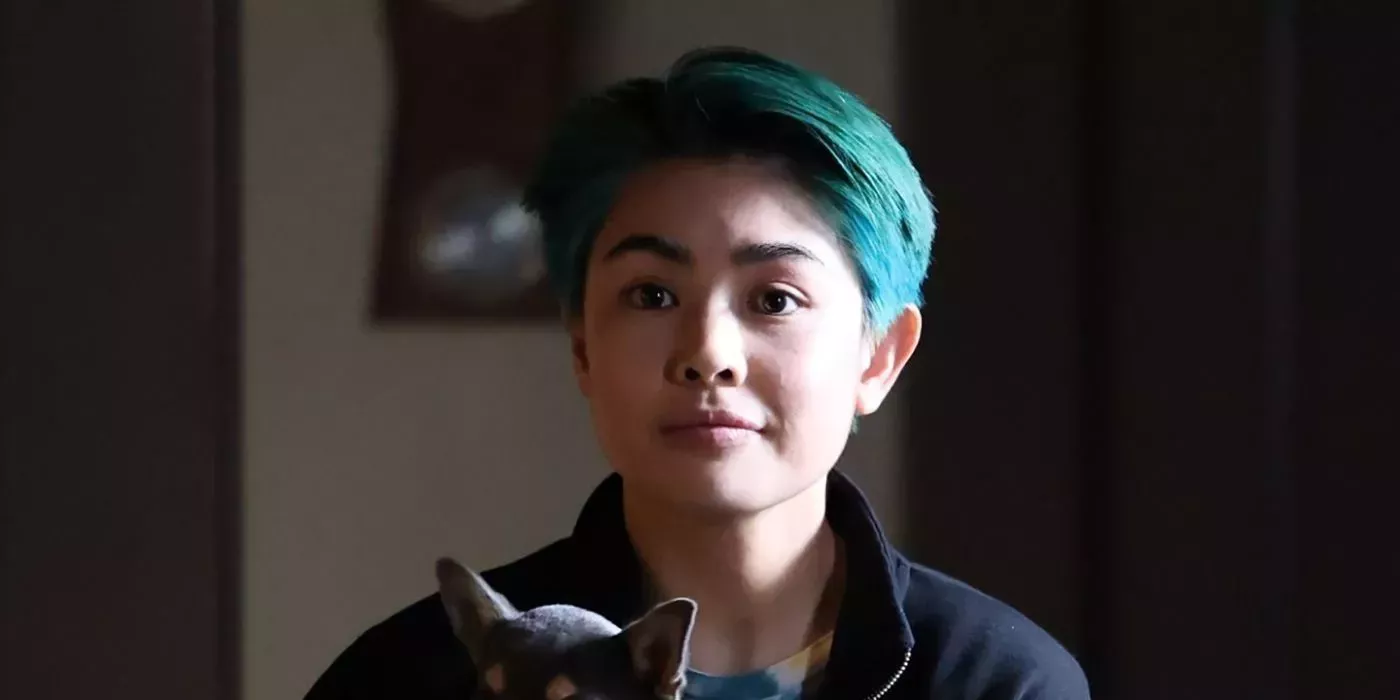 A close-up of Nico with blue hair holding a dog in Will Trent.