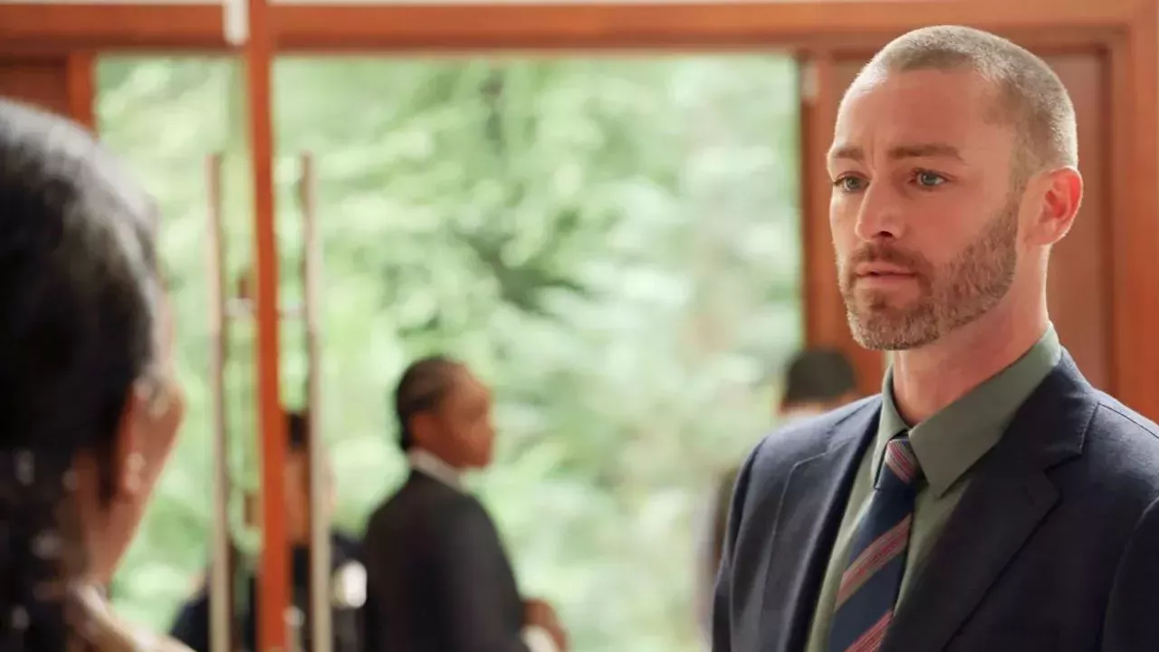 Jake McLaughlin in a suit talking to someone in a scene from Quantico.