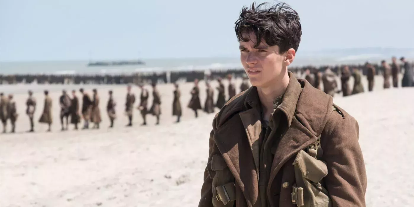 Tommy staring ahead of him with soldiers in the background in Dunkirk