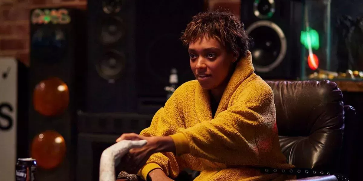 Mia sits in a bathrobe in front of an enormous speaker system in Talk to Me