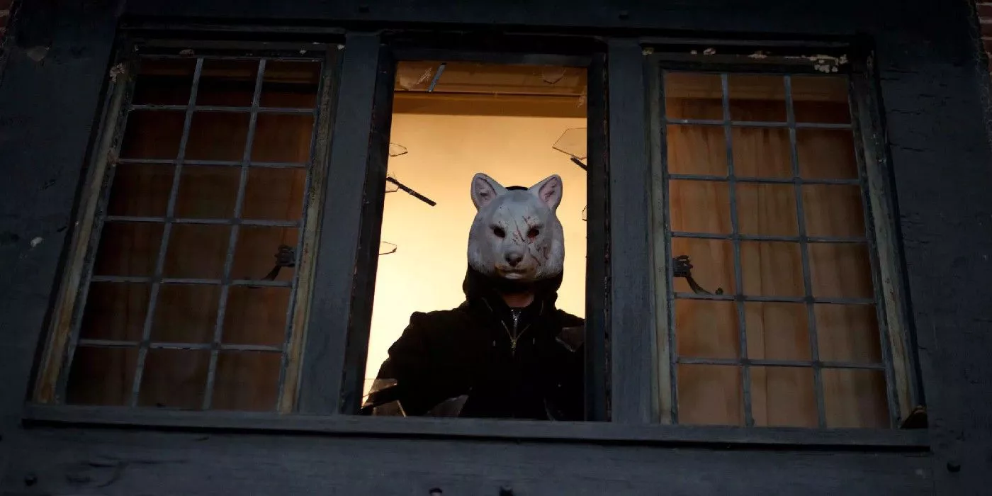 A killer with a wolf mask looks out the window in You're Next.