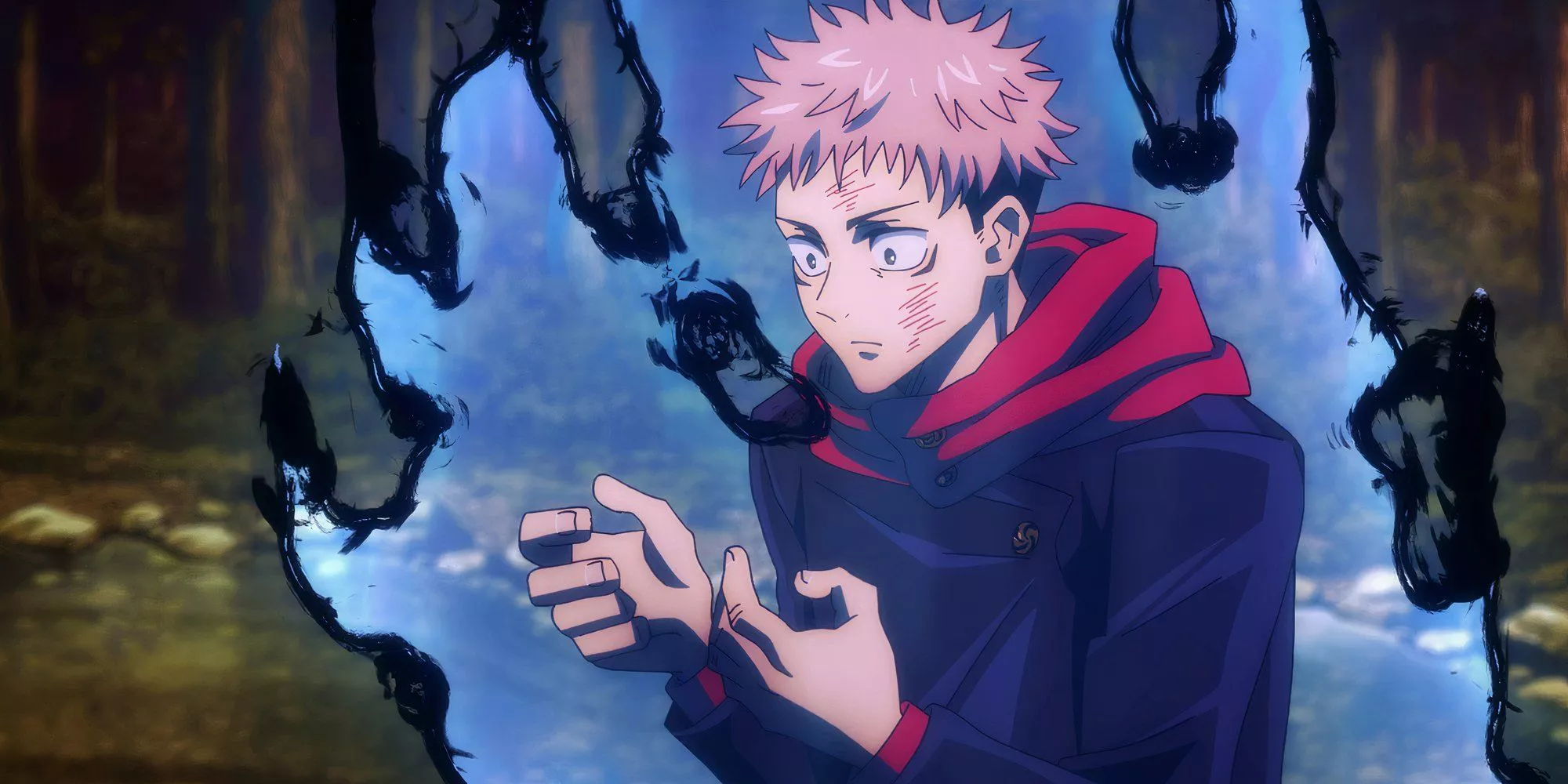 Yuji Itadori looks down at his hands in Jujutsu Kaisen while cursed energy flares up around him.