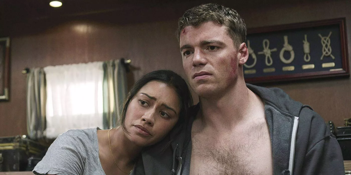 Rose rests her head on Peter's chest, him bruised with his sweater open and looking sad on The Night Agent.