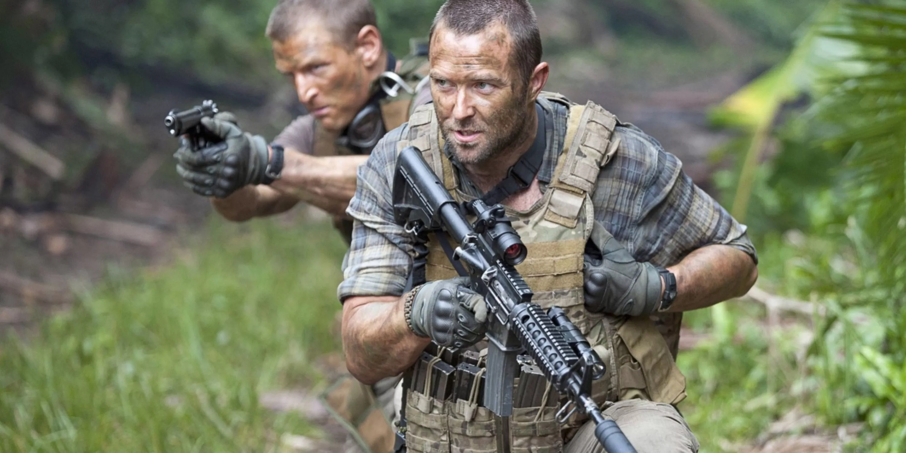 Scott and Stonebridge move through a jungle holding guns in Strike Back