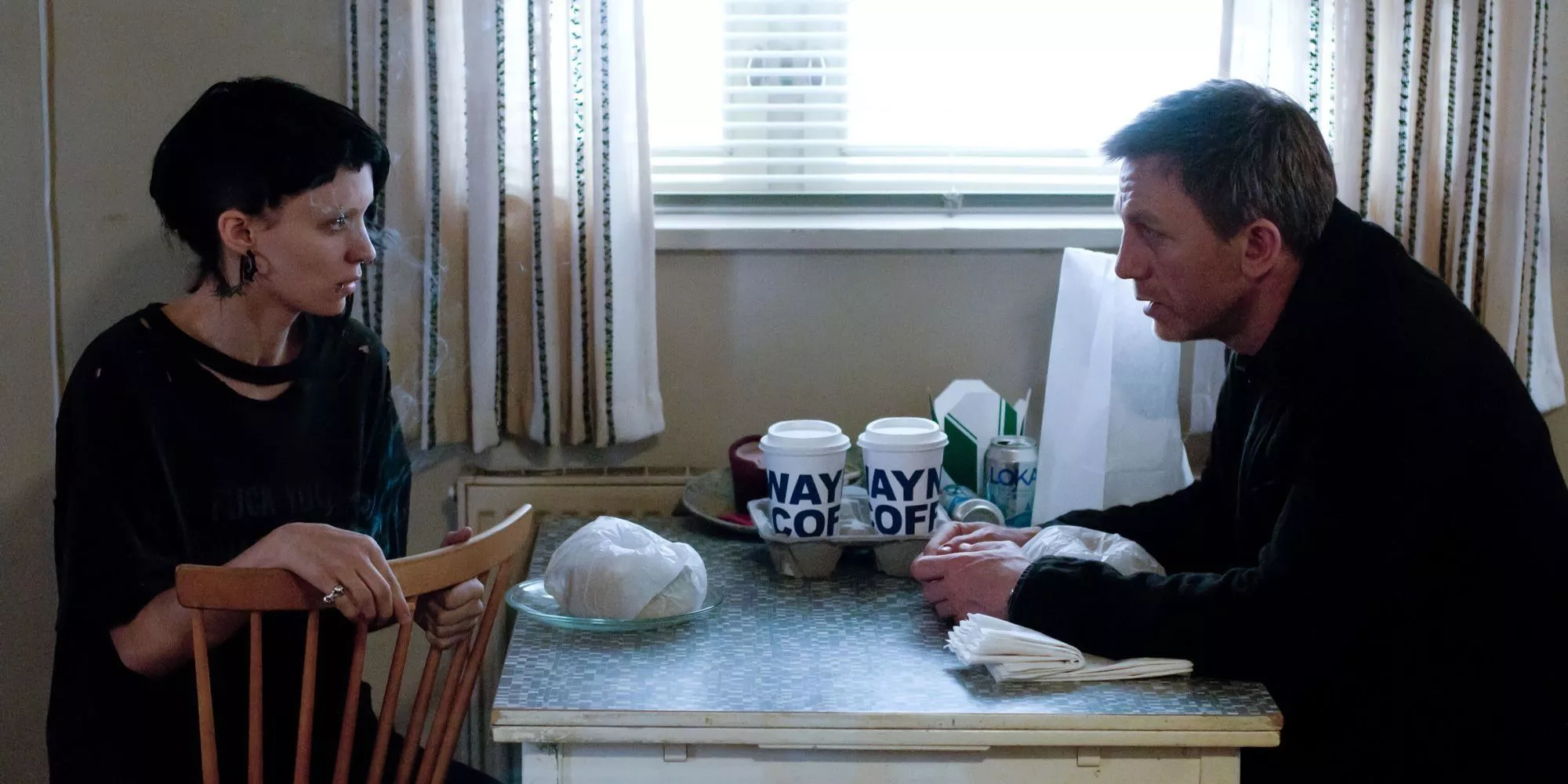 Mikael (Daniel Craig) and Lisbeth (Rooney Mara) sit at a table in The Girl with the Dragon Tattoo.