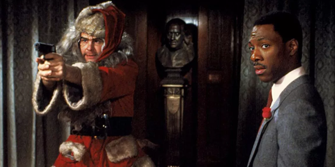 Dan Aykroyd dressed as Santa holds a gun while Eddie Murphy in a suit stands next to him.