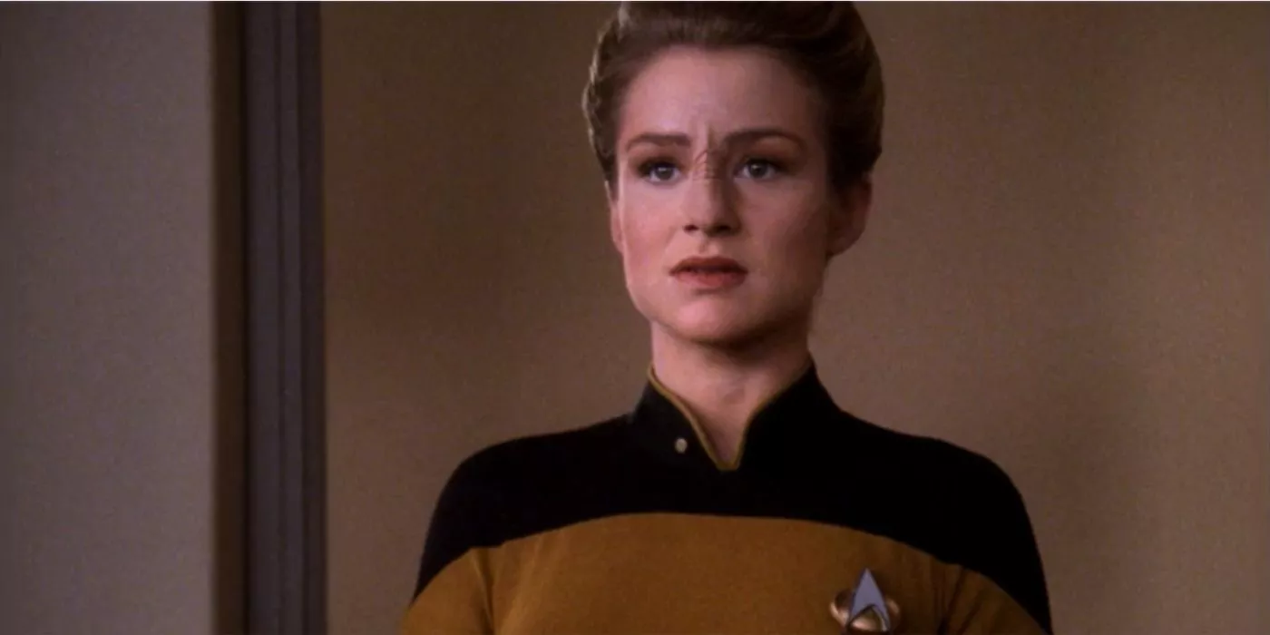 Ensign Sito Jaxa de pie contra las paredes de alfombra beige de la Enterprise D en el episodio Lower Decks de Star Trek TNG